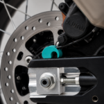Close-up of the 3Dit CFMOTO 450MT rear ABS cover installed near the rear brake assembly and axle system.